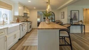 Una cocina amplia con una isla central, suelo de madera y un comedor con sillas.