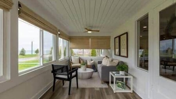Un salón espacioso con un ventanal grande, ventilador de techo y vistas al exterior.