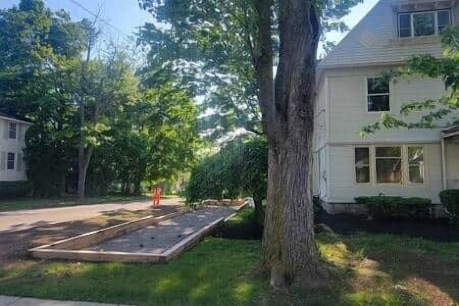 A residential area with a house, a tree, and a paved driveway.