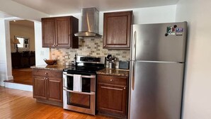 A modern kitchen with wooden cabinets, stainless steel appliances, and a tiled backsplash.
