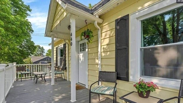 A porch with outdoor seating, a door, and a window with shutters. - LVR - The Yellow House on 3rd (Lewiston)