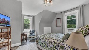 A bedroom with a bed, a TV, a desk, and a chair. - LVR - The Yellow House on 3rd (Lewiston)