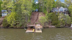 A docked house with a wooden deck and a slide leading to a dock. - Hot Tub, Fire Pit, Kayak,Water Slide, Pet Friendly (Bracey)