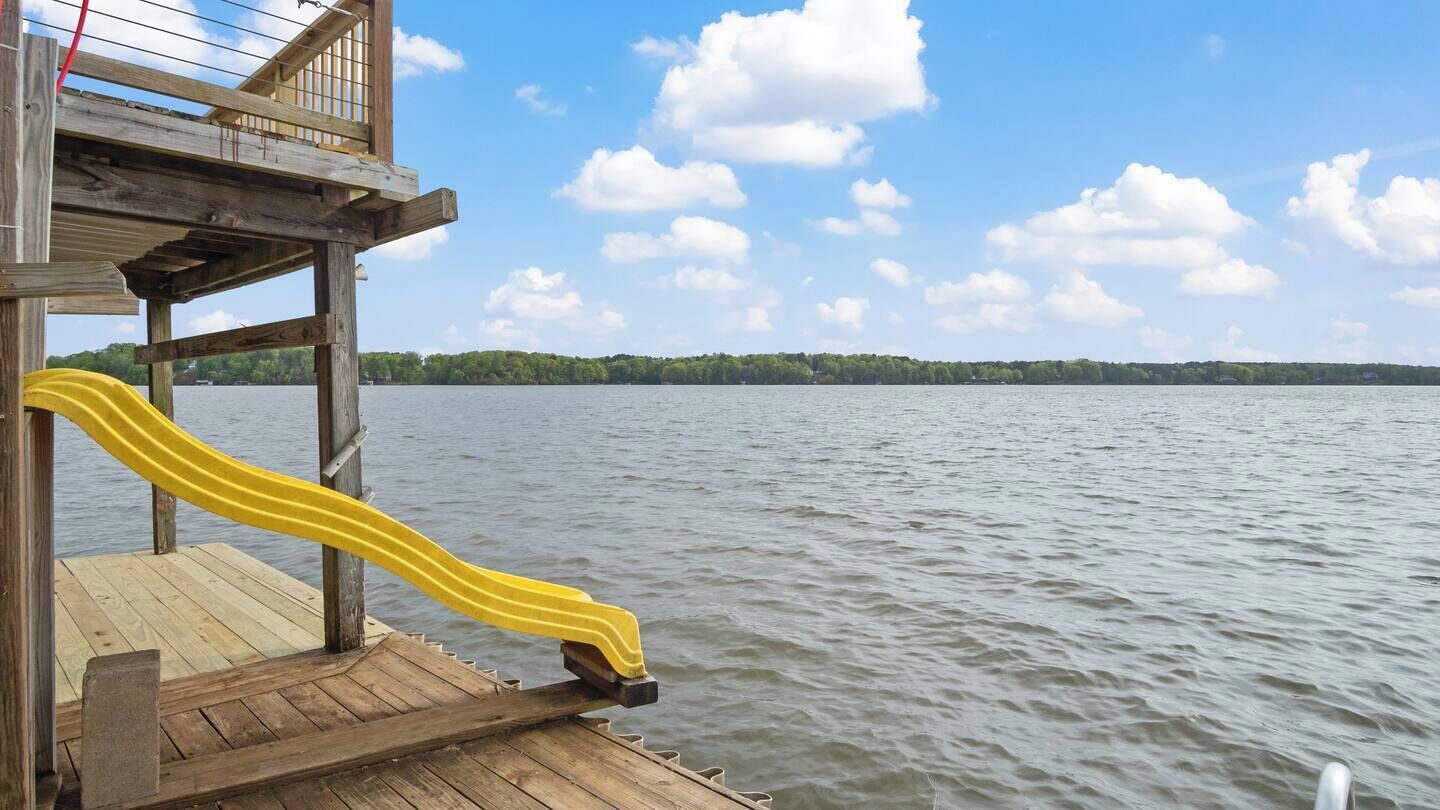 Une jetée en bois s’avançant dans un lac, avec un toboggan jaune.
