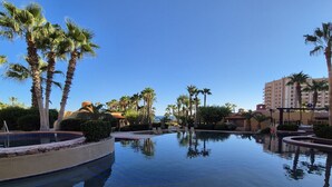 Une piscine bordée de palmiers, sous un ciel bleu azur.