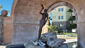 Une statue représentant une femme debout sur des rochers, sous une structure en forme d’arche.