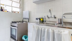 Μια κουζίνα με γκαζιέρα, φούρνο, νεροχύτη από ανοξείδωτο ατσάλι και ένα παράθυρο με θέα.