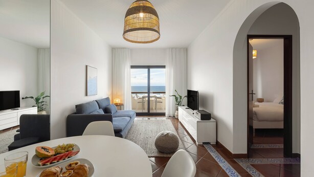 A modern living room with a dining area, a large window with a view, and a cozy seating arrangement. - Pérola do Mar - Atlantic Escape (Caldas da Rainha)
