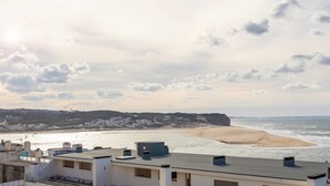 A coastal view with buildings, a beach, and a cliff. - Pérola do Mar - Atlantic Escape (Caldas da Rainha)
