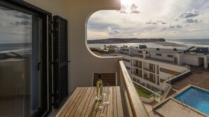 A balcony with a wooden table, a bottle of wine, and two glasses. A pool is visible below the balcony. - Pérola do Mar - Atlantic Escape (Caldas da Rainha)