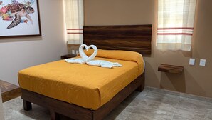 Ein Bett mit einer gelben Bettdecke und zwei weißen Handtüchern, die zu einem Herz geformt sind.
