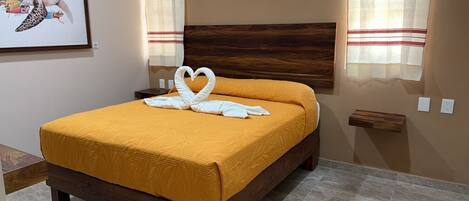 Un lit recouvert d’une couvre-lit jaune, avec deux serviettes blanches disposées en forme de cœur.