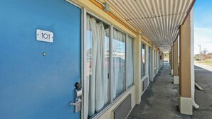 A corridor with numbered doors, a covered walkway, and a building exterior. - Luxury Inn By Hotel O Hattiesburg, MS (Hattiesburg)