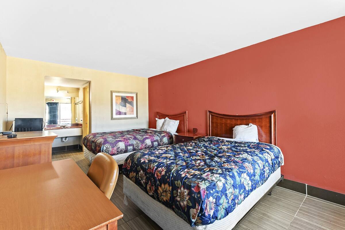 Une chambre d’hôtel avec deux lits, un bureau et une chaise.