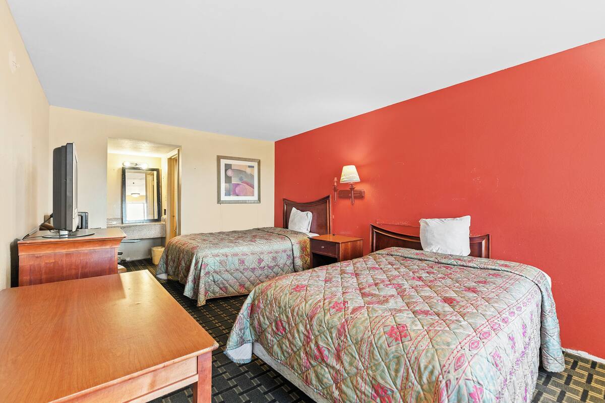 Une chambre d’hôtel avec deux lits, un bureau, une télévision et une lampe.