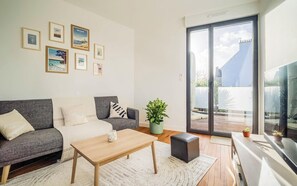 Ein modernes Wohnzimmer mit einem grauen Sofa, einem Holztisch und einem großen Fenster mit Blick auf die Stadt.