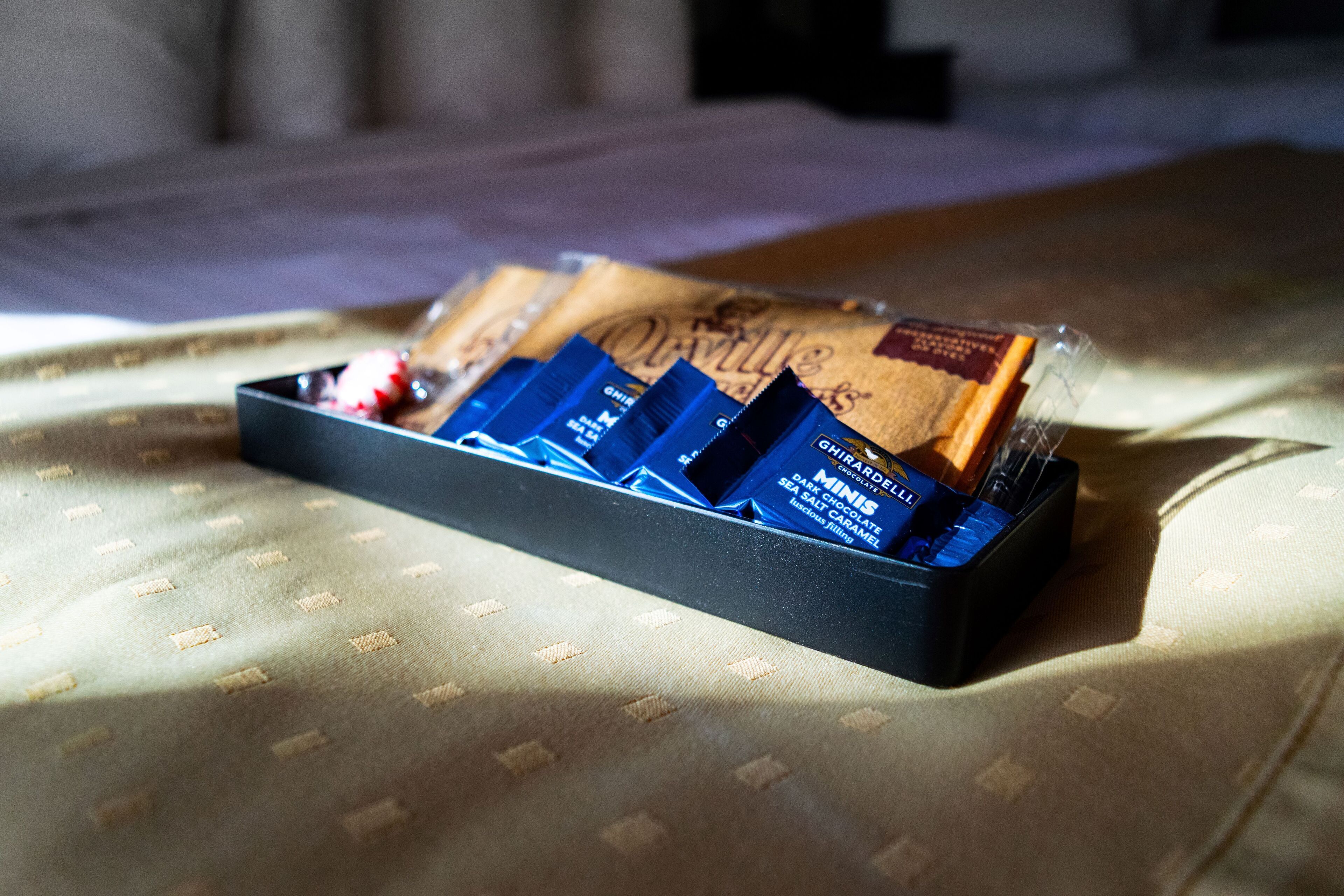 Een schaal met chocolade op een bed met een decoratieve sprei.