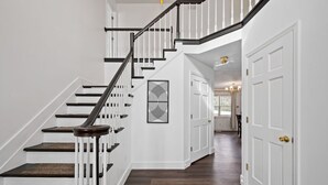 A staircase with white railings and dark steps, leading to a room with a door and a chandelier.