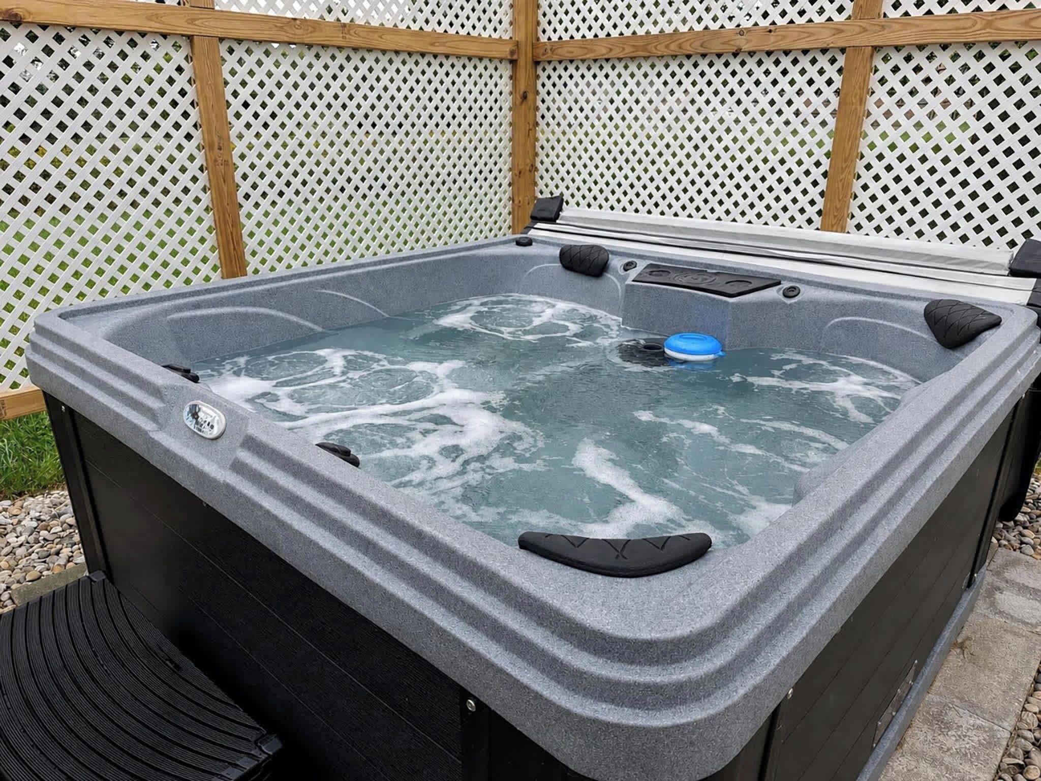 A hot tub with a wooden frame, a control panel, and a blue lid.