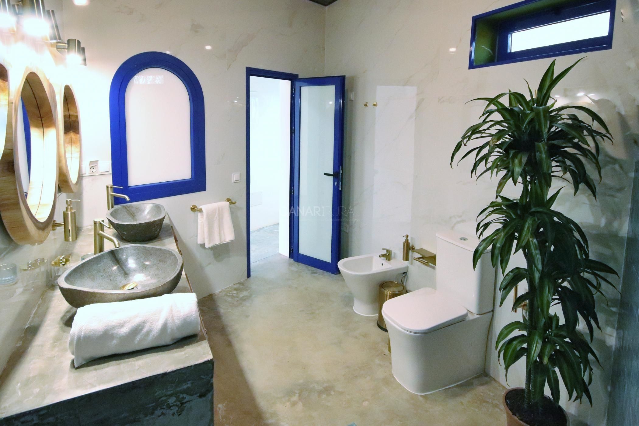 Ein Badezimmer mit einem großen Waschbecken, einem Bidet, einer Toilette und einer Topfpflanze.