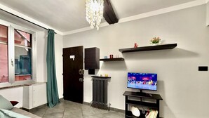 A living room with a sofa, a television, a radiator, and a door. - DIMORA DI PRE   ACQUARIO   GENOVABB.IT (GENOVA)