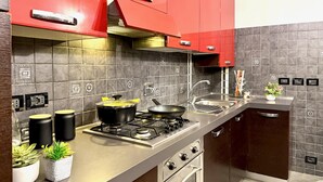 A modern kitchen with red cabinets, a stainless steel countertop, and a built-in oven. - DIMORA DI PRE   ACQUARIO   GENOVABB.IT (GENOVA)