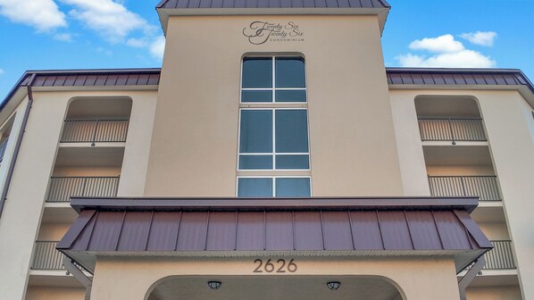 A building with a beige facade, a central window, and balconies. The number 2626 is visible at the bottom. - Beachside 1st Floor Condo with Patio,Heated Pool & Gas BBQ – 3 Min Walk to Beach (Daytona Beach Shores)