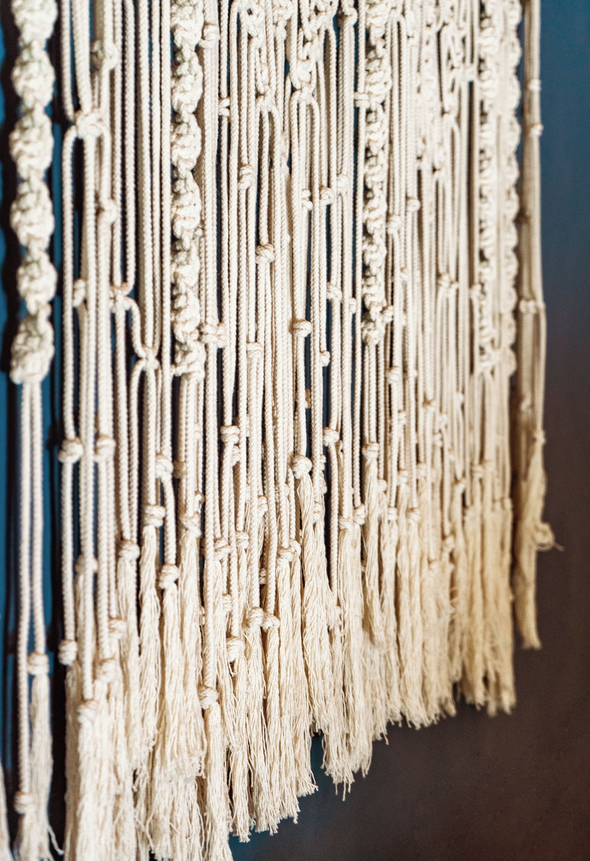 Une décoration murale en macramé, ornée de motifs complexes et de franges.
