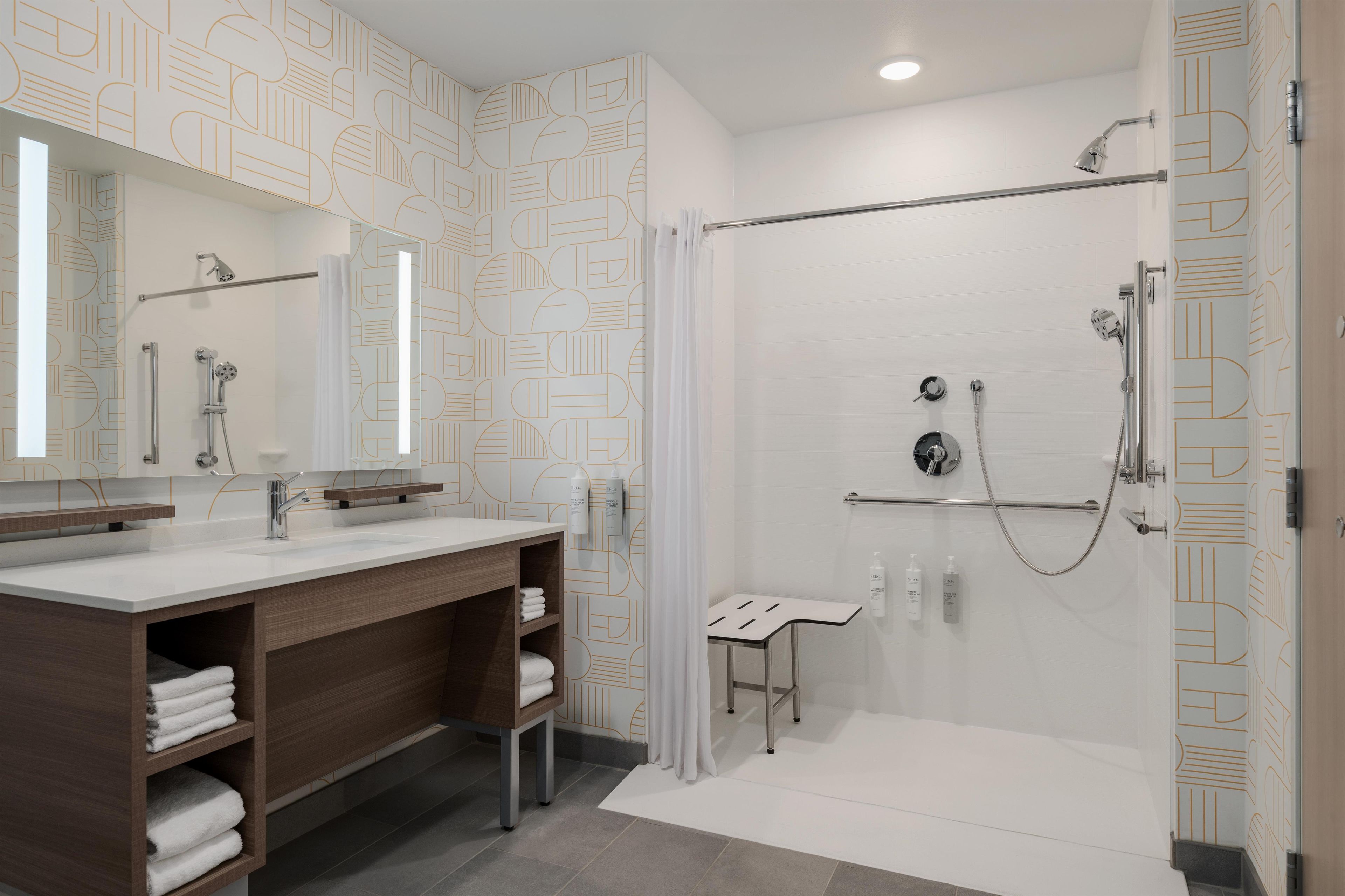 A modern bathroom with a shower, a vanity with a mirror, and a towel rack.