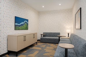 Una habitación moderna con papel tapiz estampado, un sofá, una mesita, un armario y un cuadro en la pared.