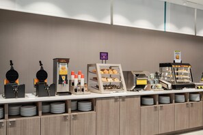 A breakfast buffet with waffle makers, coffee dispensers, and a variety of pastries. - Home2 Suites By Hilton Lafayette I-10 (Lafayette)
