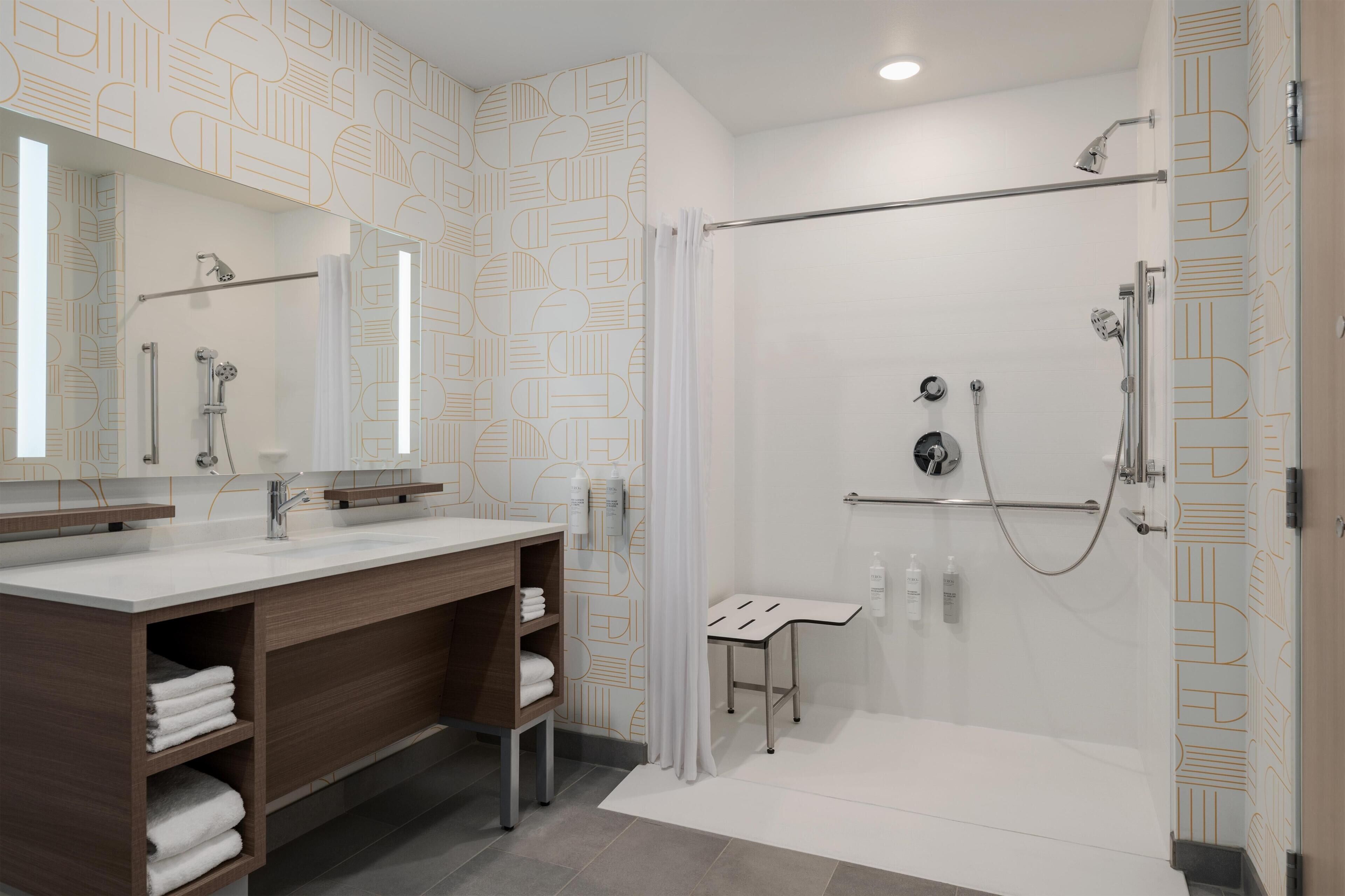 Une salle de bain moderne équipée d’une douche, d’un meuble-lavabo avec un miroir et d’un porte-serviettes.