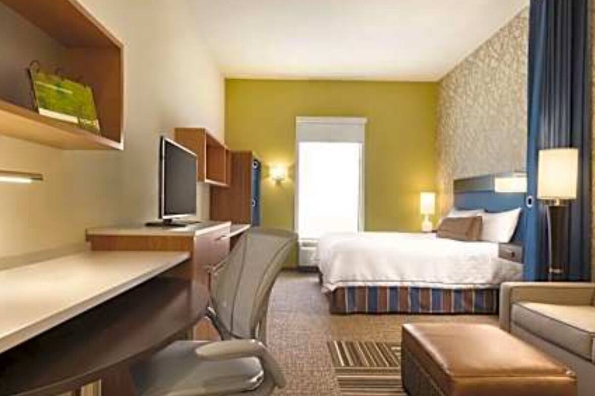 A hotel room with a bed, a desk, a chair, a TV, and a sofa.