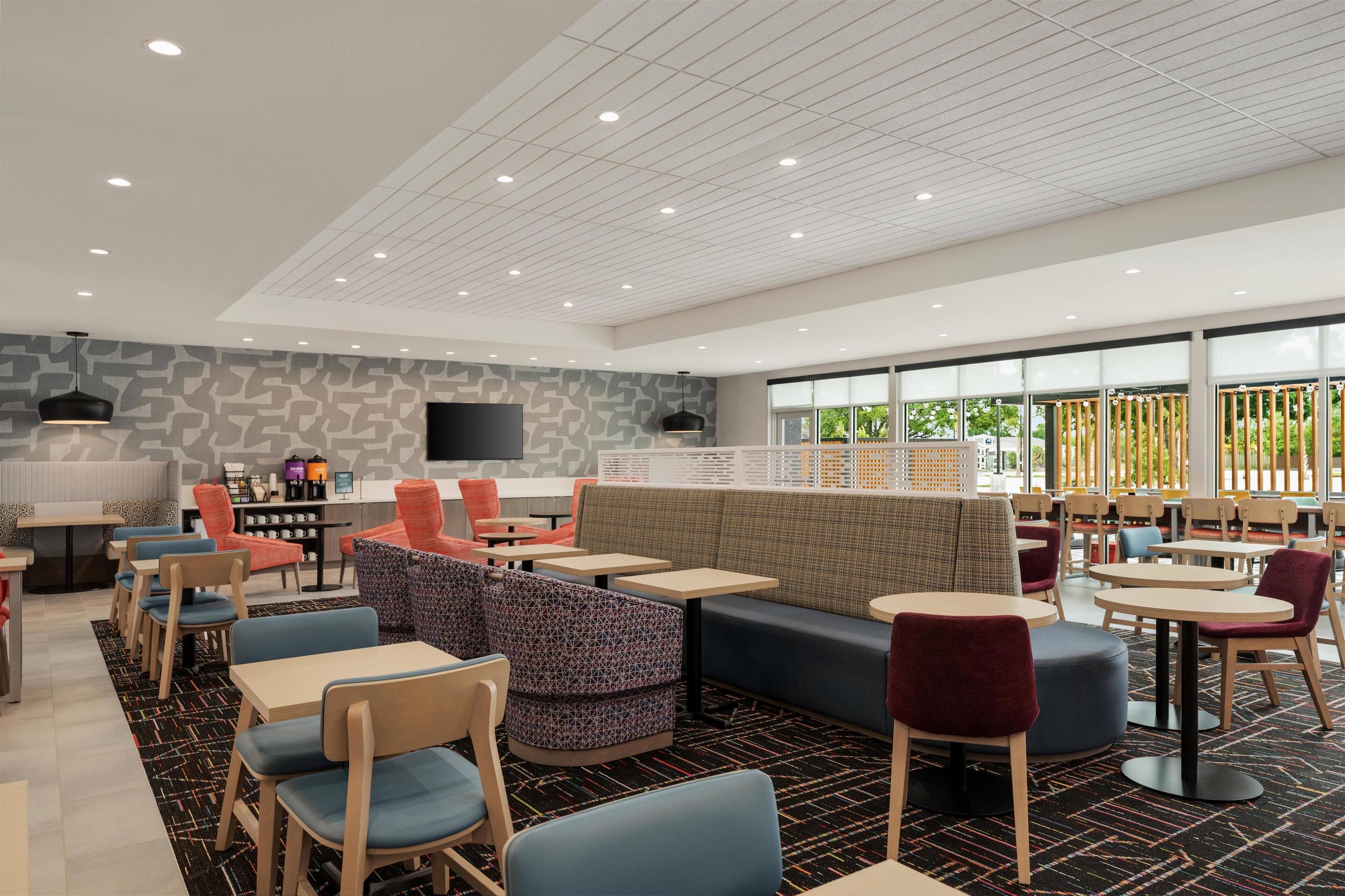 A modern indoor space with seating arrangements, tables, and a large window providing natural light.