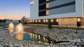 A modern building with a sign reading 'HOME 2' and a water feature with fountains. - Home2 Suites By Hilton Lafayette I-10 (Lafayette)