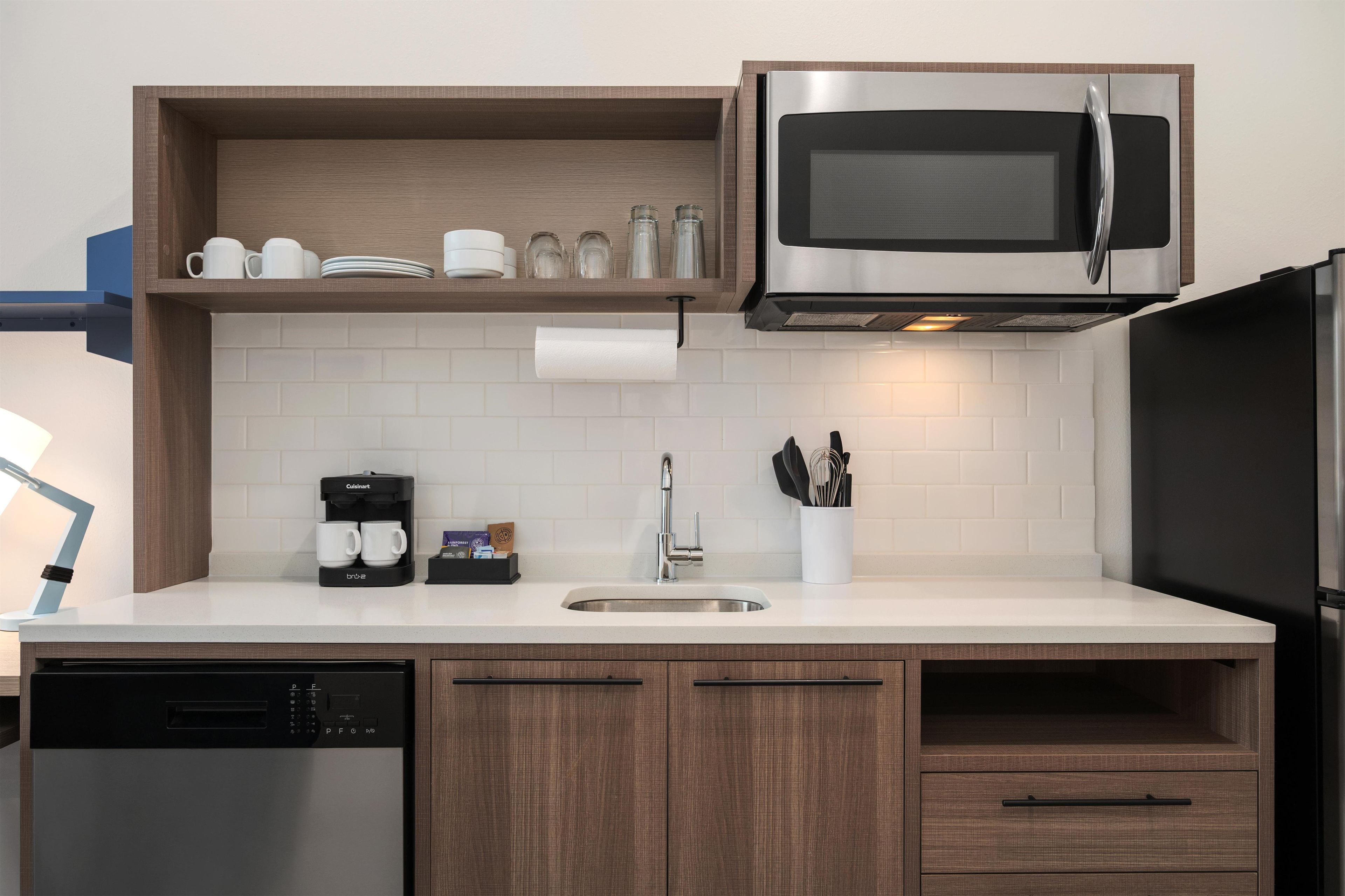 Eine moderne Küche mit Einbau-Mikrowelle, Kaffeemaschine und Geschirrspüler.