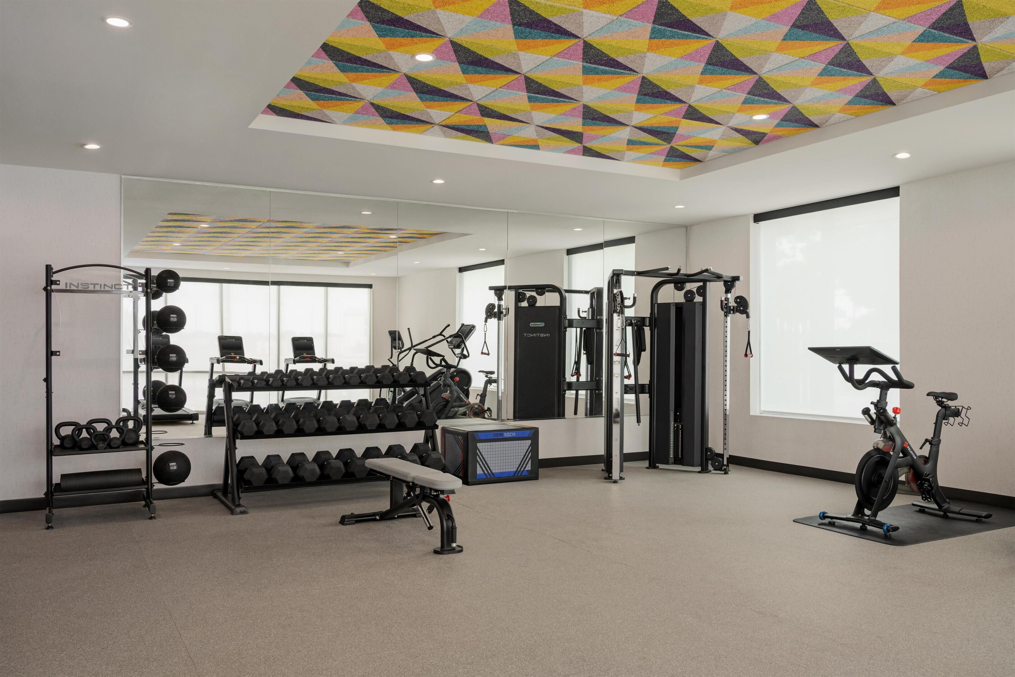 A gym with weight racks, dumbbells, a bench, and exercise equipment.