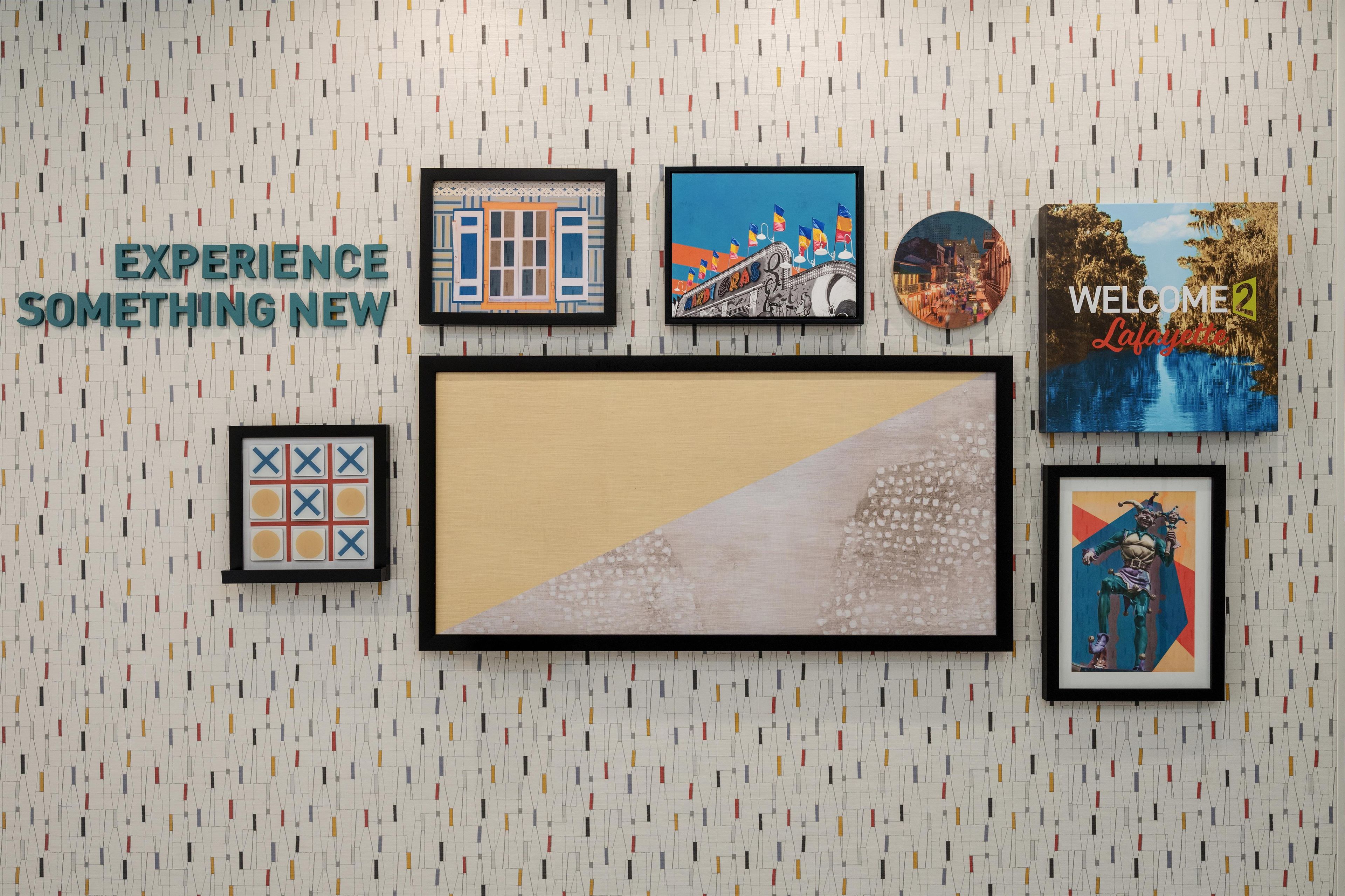 Un mur orné de divers tableaux encadrés, avec une grande œuvre d’art placée au centre.