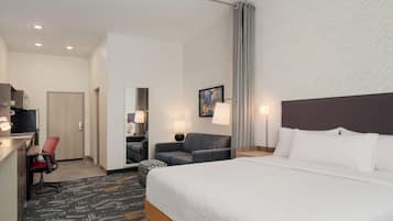 Een hotelkamer met een bed, een bureau, een stoel, een bank en een schilderij aan de muur.