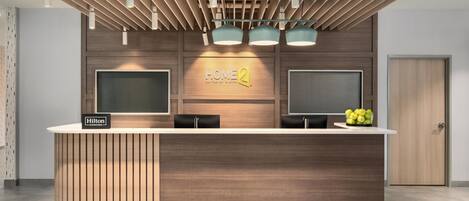 A modern hotel reception desk with a wooden finish, two monitors, and a sign that reads 'HOME2'.