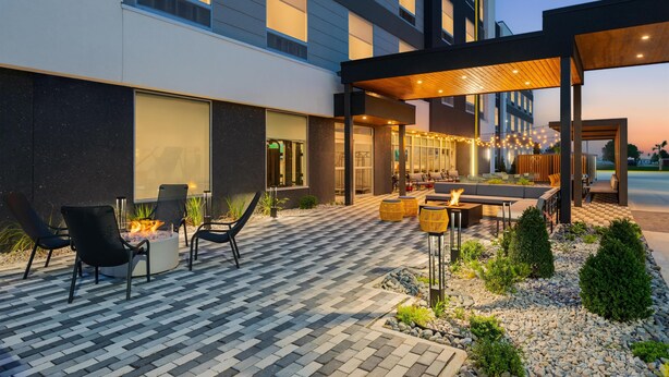 A modern outdoor seating area with fire pit, chairs, and a covered patio. - Home2 Suites By Hilton Lafayette I-10 (Lafayette)