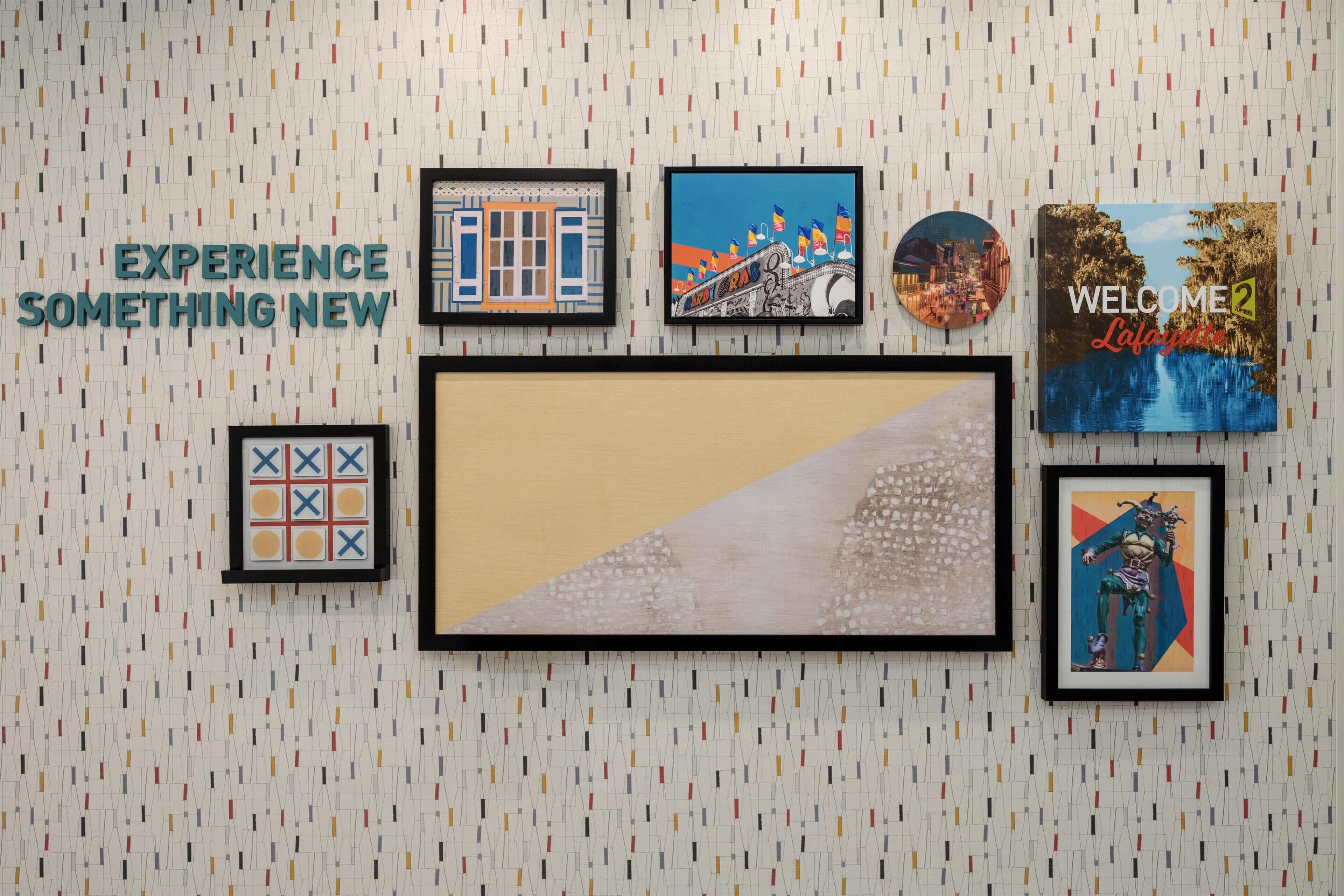 A wall with various framed artworks and a large central piece.