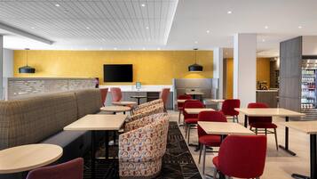 A modern restaurant with a high ceiling, a flat-screen TV, and a variety of seating options including booths and tables.