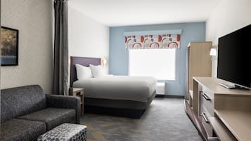 A hotel room with a bed, a sofa, a TV, and a desk.