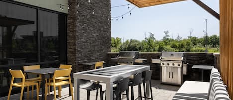 An outdoor patio with a grill, seating, and string lights.