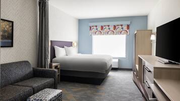 A hotel room with a bed, a sofa, a TV, and a desk.