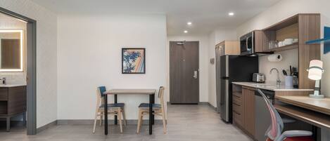 A modern kitchen with a dining area, a microwave, refrigerator, and a small table with chairs.