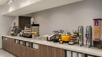 A self-service breakfast station with various food dispensers, including oatmeal and milk.