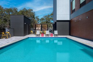Una piscina con sillas de descanso y una valla.