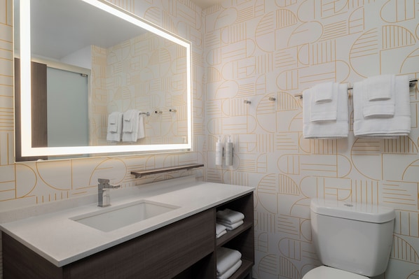 Un baño moderno con un espejo grande, dos lavamanos, un inodoro y un perchero para toallas.